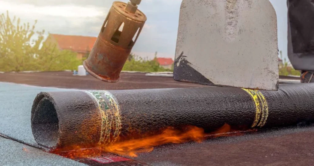 Brander verwarmt een rol bitumen dakbedekking op een plat dak in Nieuwegein