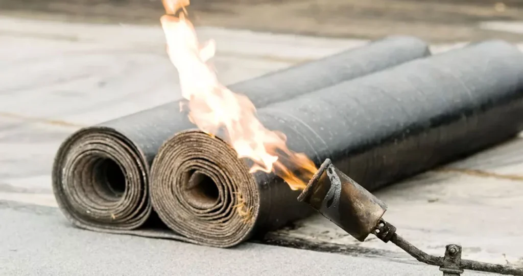 Twee rollen bitumen dakleer met een brandende gasbrander ernaast in Nieuwegein