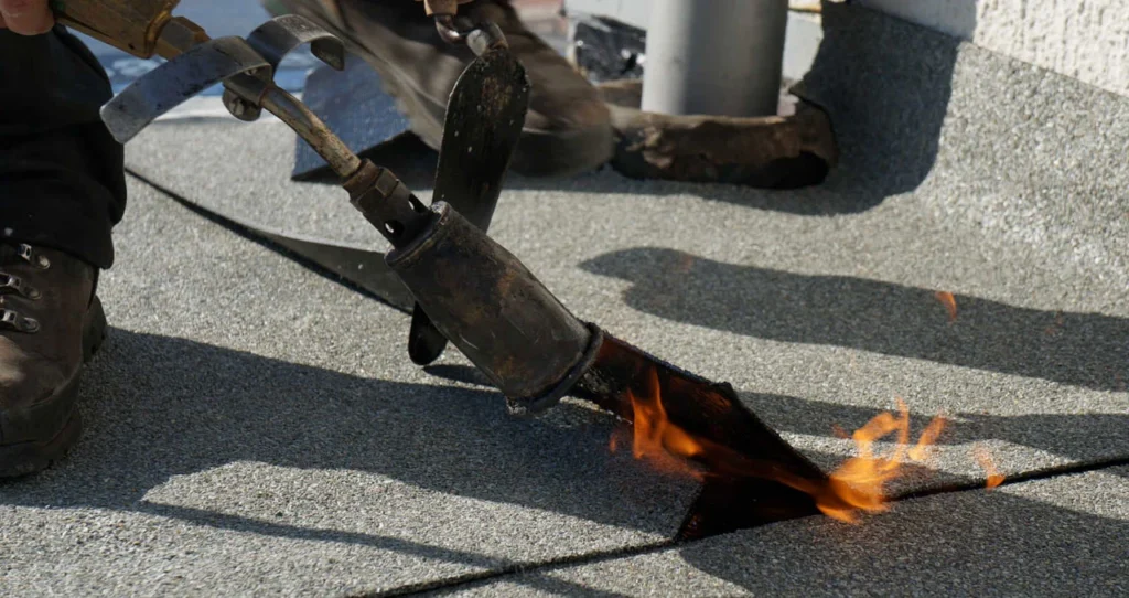 Dakdekker brandt een bitumen dakbaan vast op een plat dak in Nieuwegein