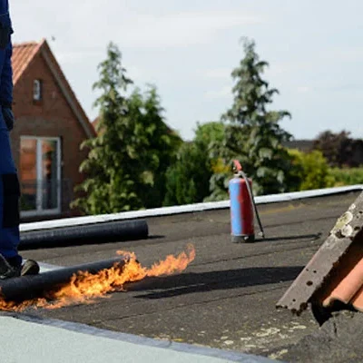 Dakdekker brandt dakleer op een plat dak naast een pannendak in Vianen