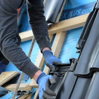 Dakdekker haakt een zwarte dakpan in op de panlat in Vianen